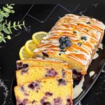 Sliced blueberry bread on a dark platter on a dark surface.