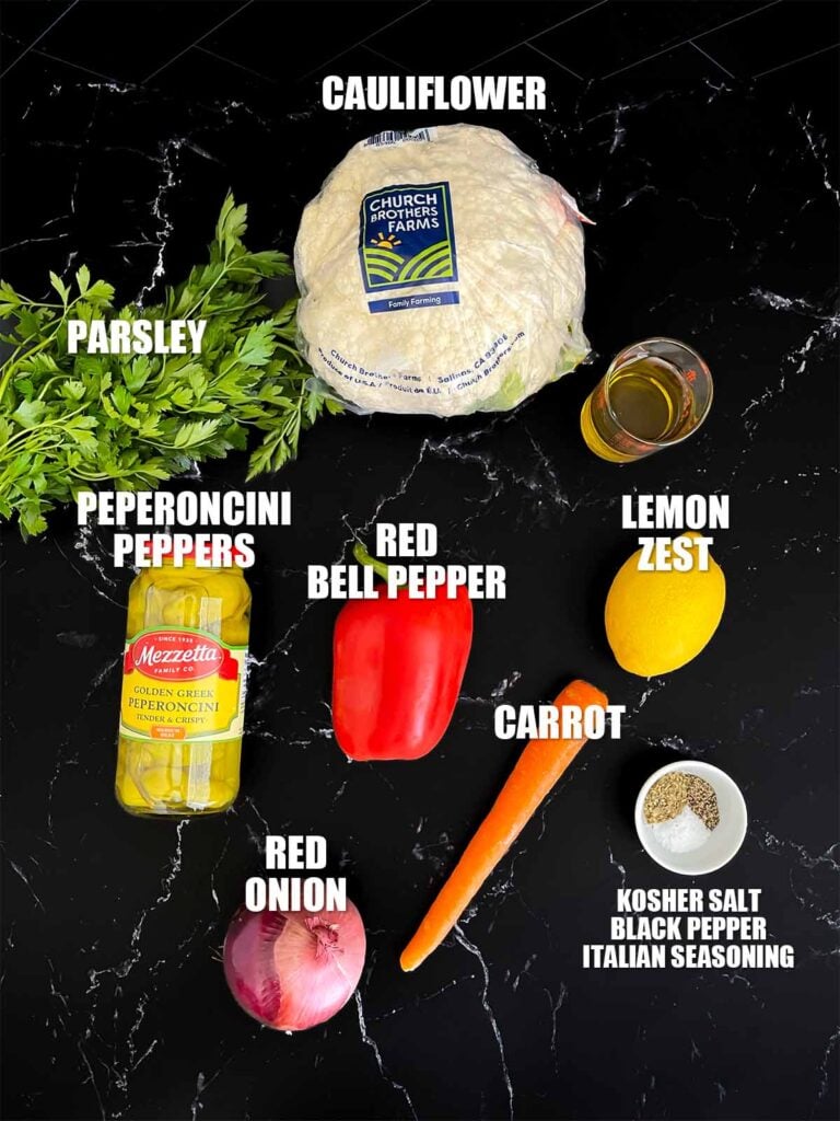 Marinated cauliflower salad recipe ingredients on a dark surface.