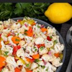 Marinated cauliflower salad in a dark bowl on a dark surface.