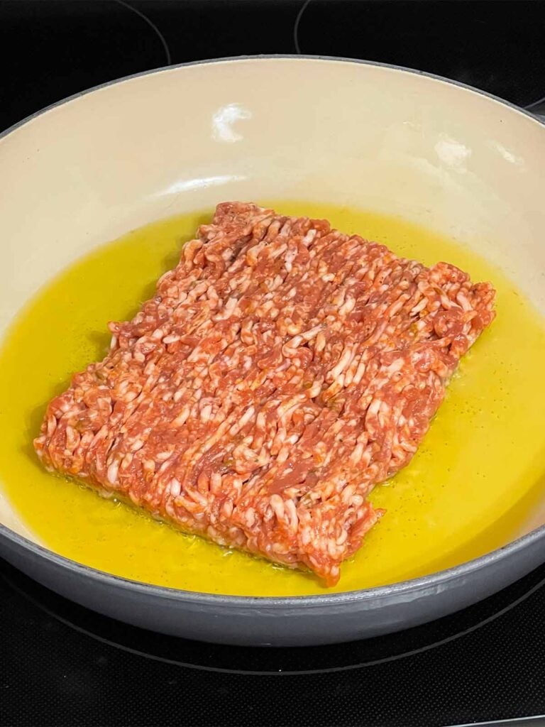 Ground sausage in olive oil in a skillet.