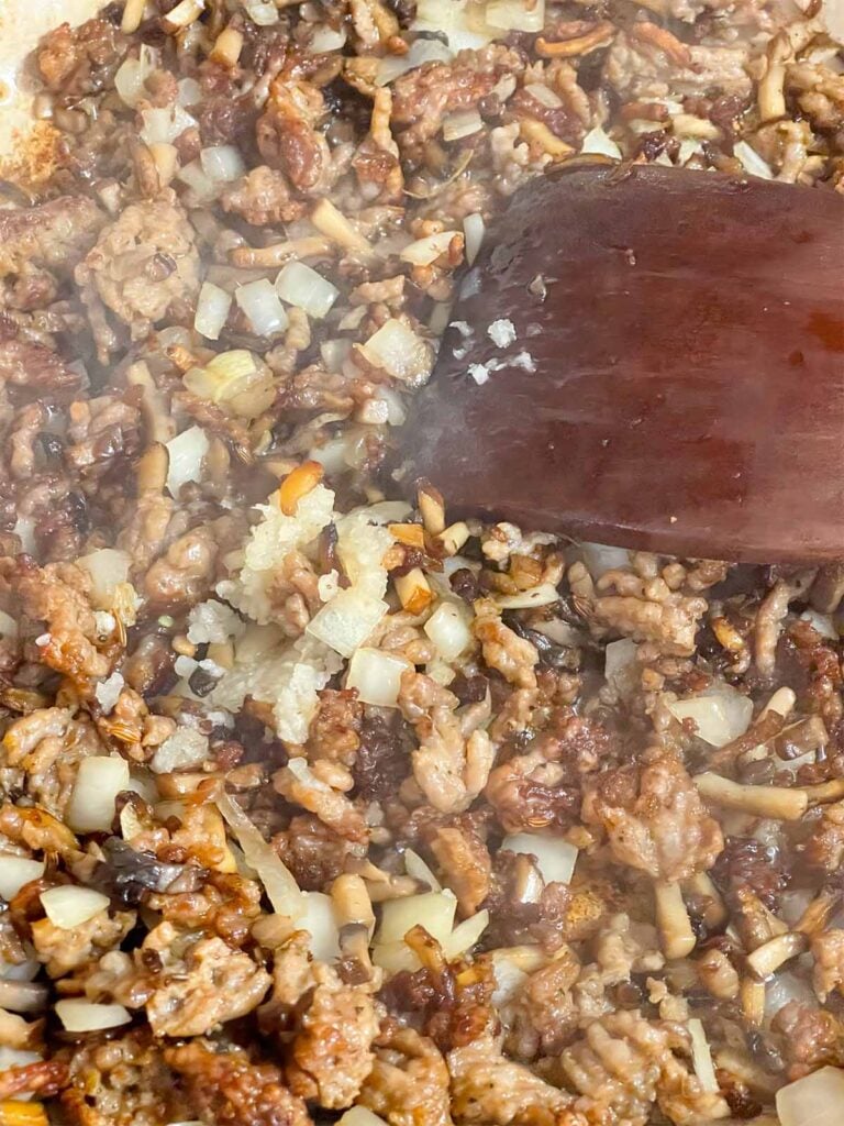 Adding garlic to Pasta alla Norcina sauce ingredients.