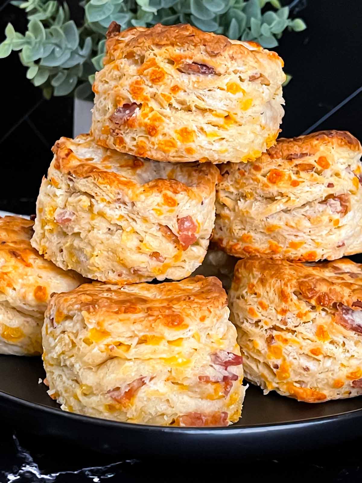 Bacon cheddar biscuits stacked on a dark plate.