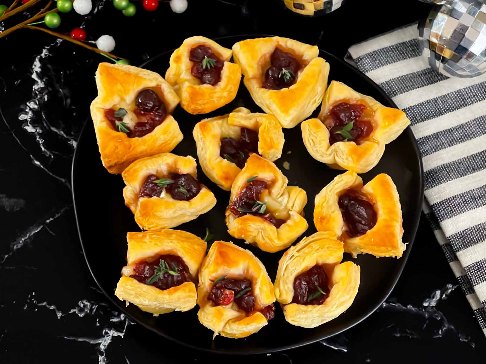 Cranberry brie bites on a dark round platter.