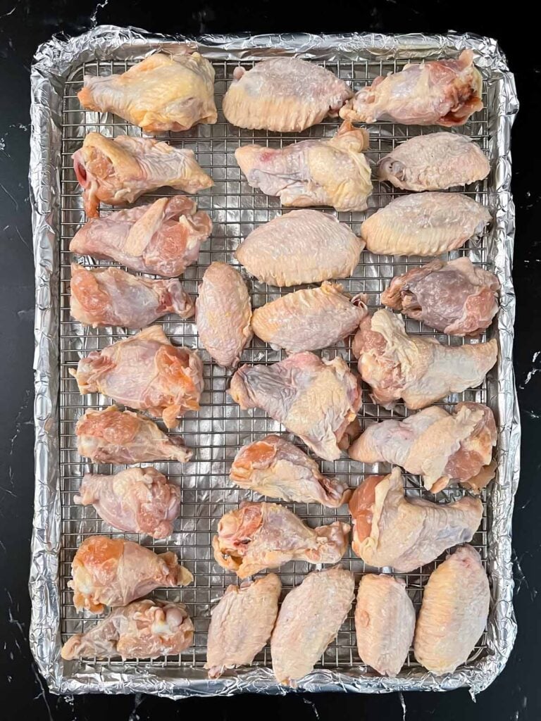 Raw chicken wings on a wire rack.