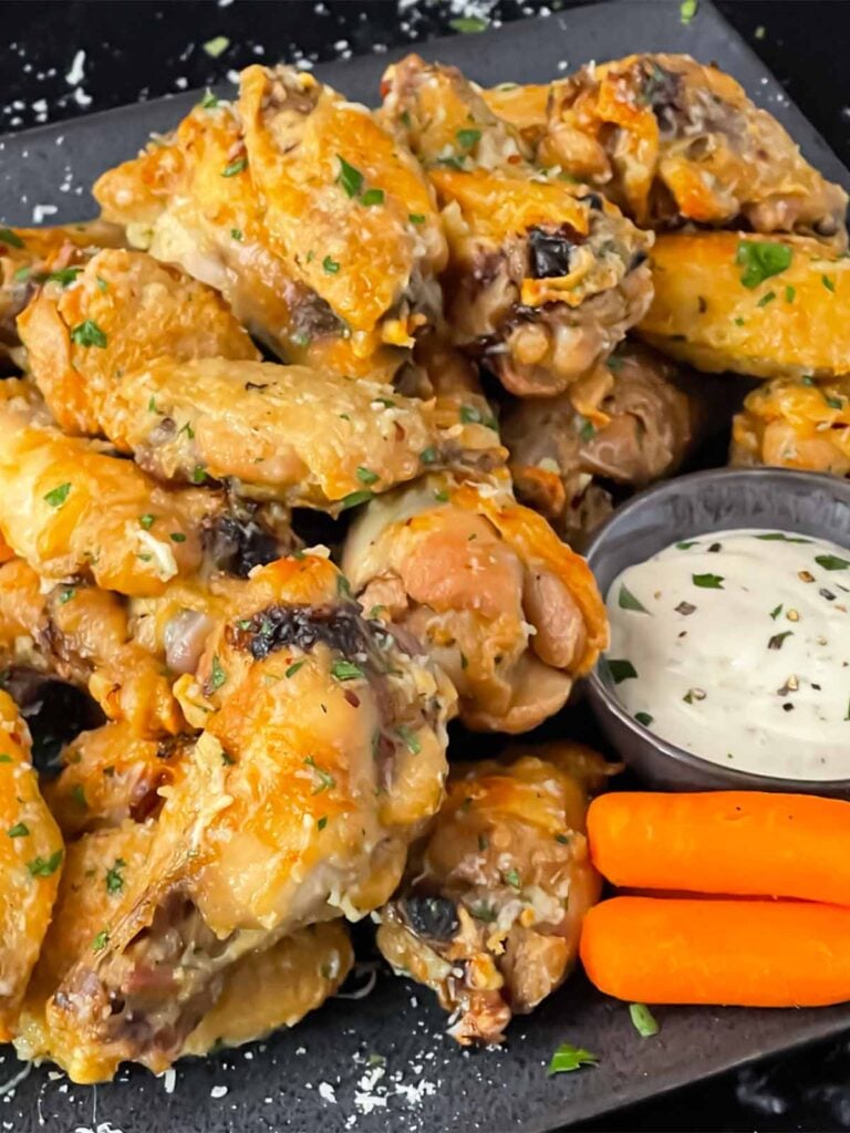Garlic Parmesan chicken wings on a dark plate.