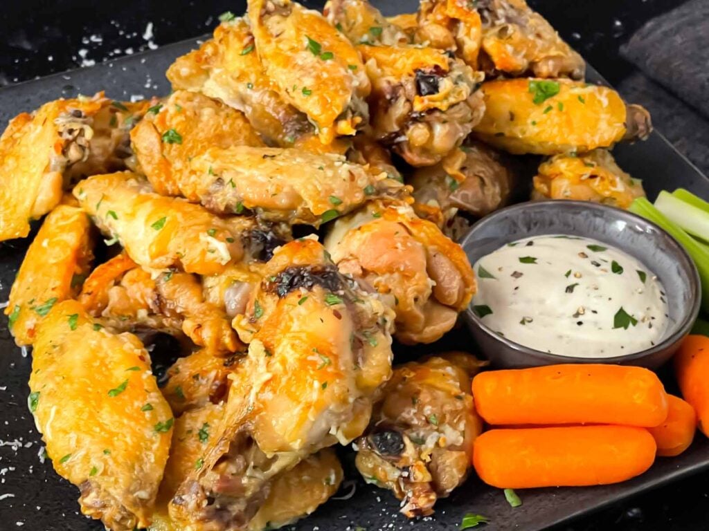 Garlic Parmesan chicken wings on a dark plate.