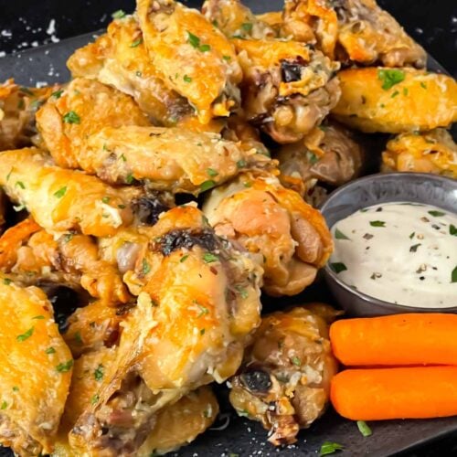 Garlic Parmesan chicken wings on a dark plate.