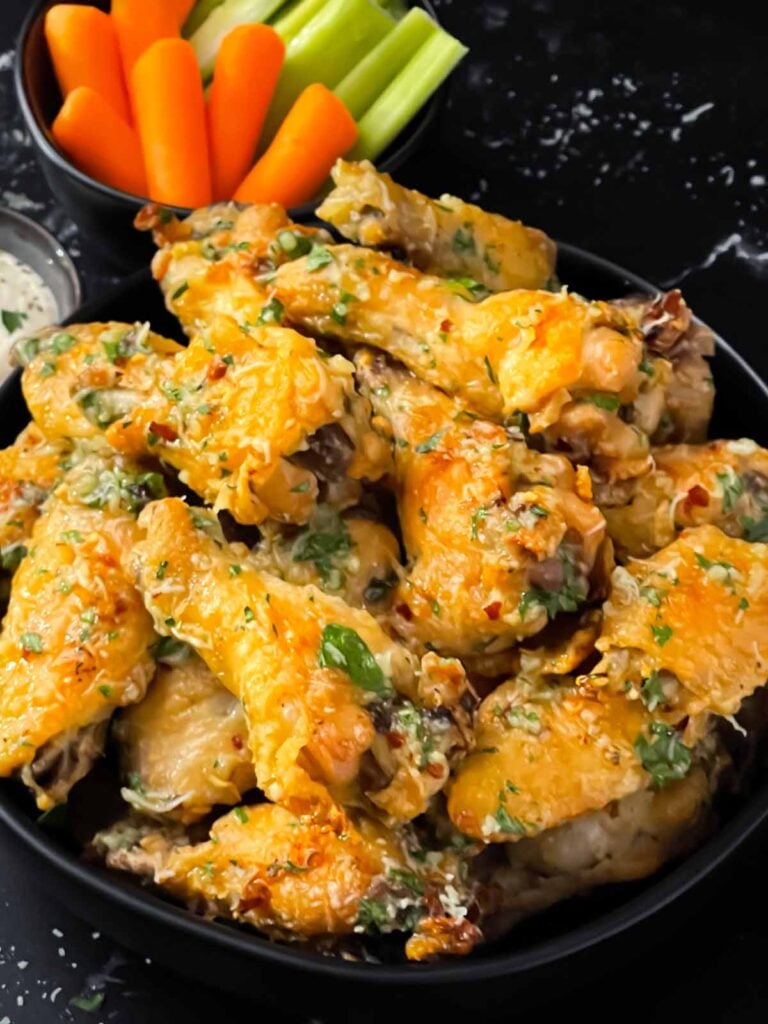 Garlic Parmesan chicken wings on a dark bowl.