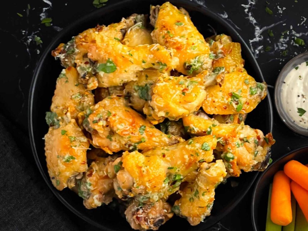 Garlic Parmesan chicken wings on a dark bowl.