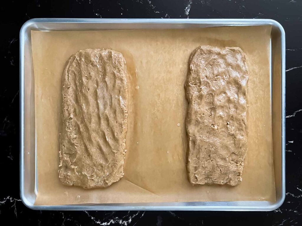 Chai biscotti dough shaped into loaves on a baking sheet.
