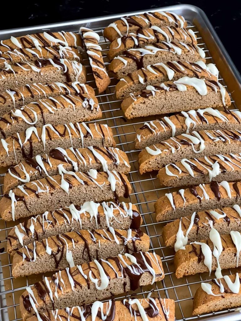 Chai biscotti with a chocolate drizzle on a wire rack.