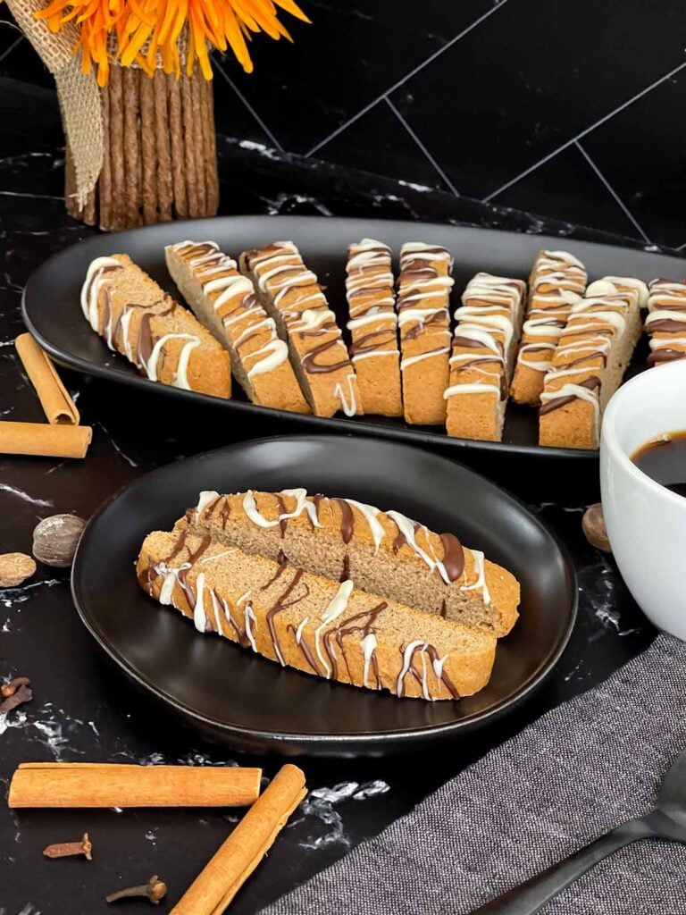 Chai biscotti on a dark plate with coffee.