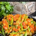 Green beans with tomato sauce in a dark bowl.