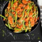 Green beans with tomato sauce in a dark bowl.