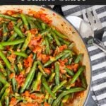 Green beans with tomato sauce in a dark bowl.