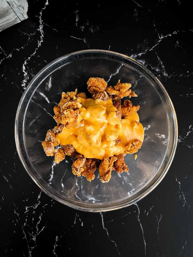 Bang Bang chicken being mixed together in glass bowl.