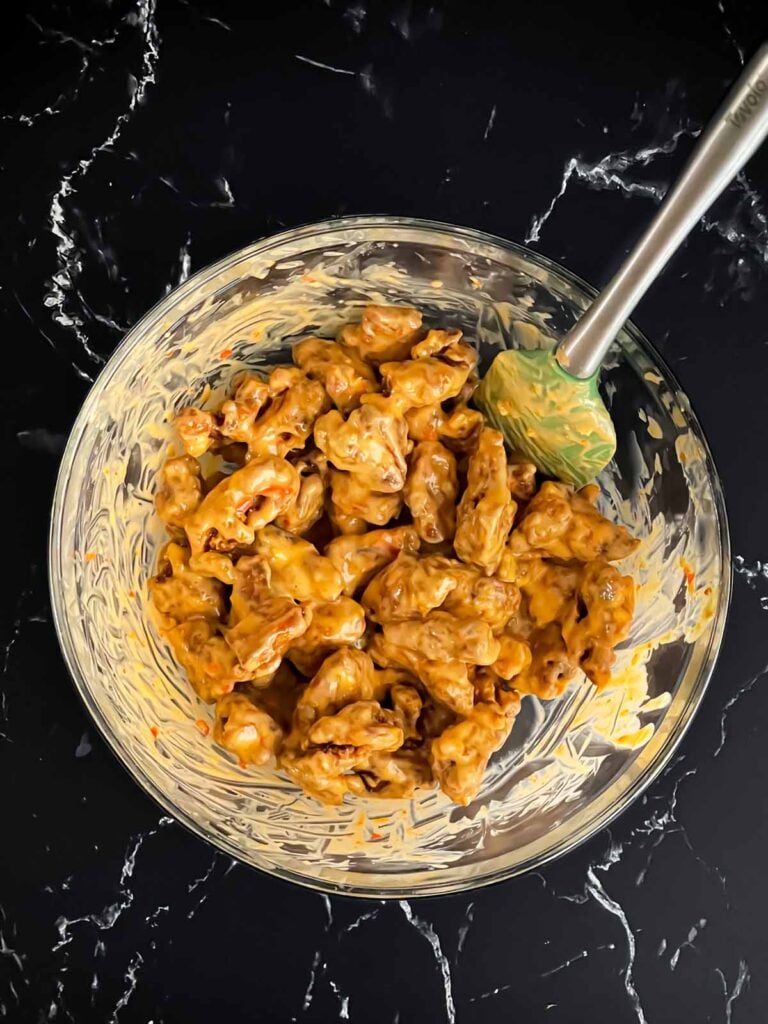 Bang Bang chicken being mixed together in glass bowl.