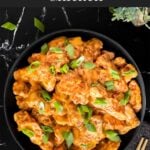 Bang Bang Chicken in a dark bowl, garnished with green onion.