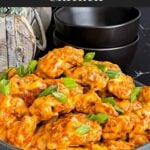 Bang Bang Chicken in a dark bowl, garnished with green onion.