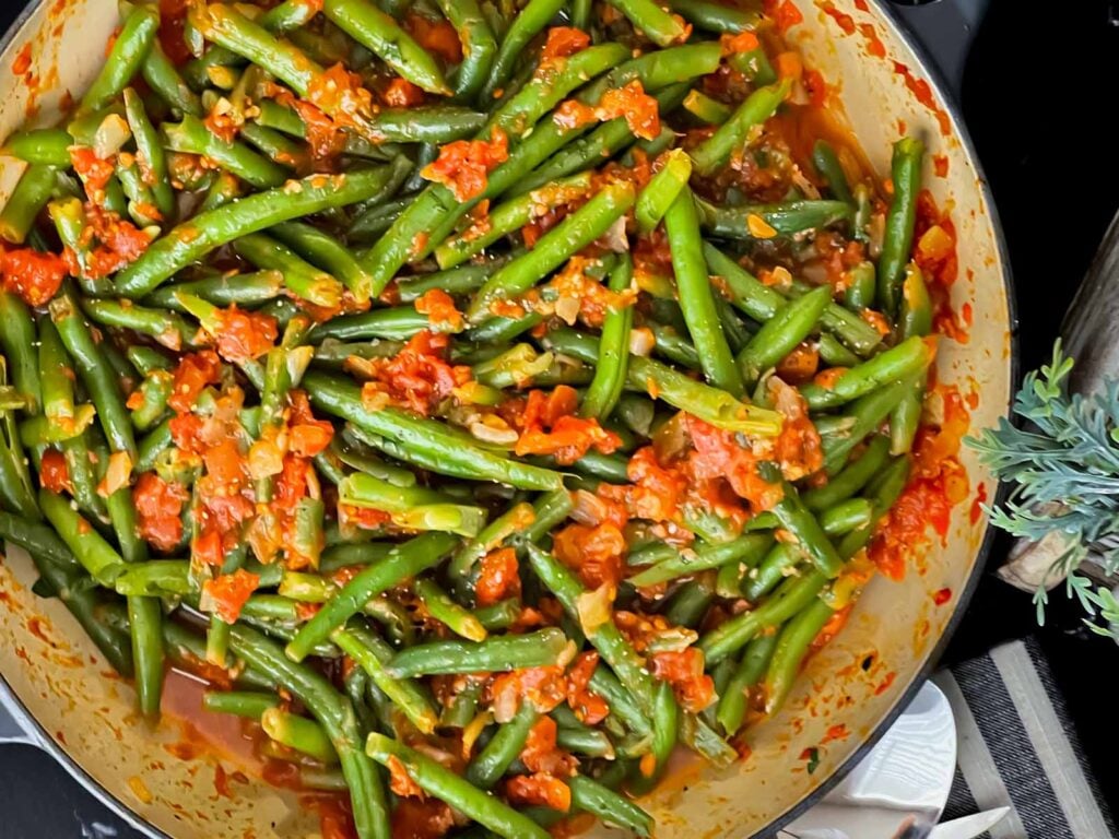 Green beans with tomato sauce in a dark bowl.