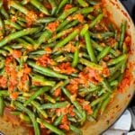 Green beans with tomato sauce in a dark bowl.