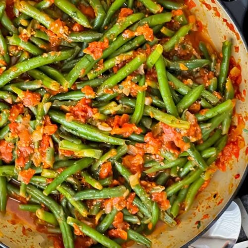 Green beans with tomato sauce in a dark bowl.