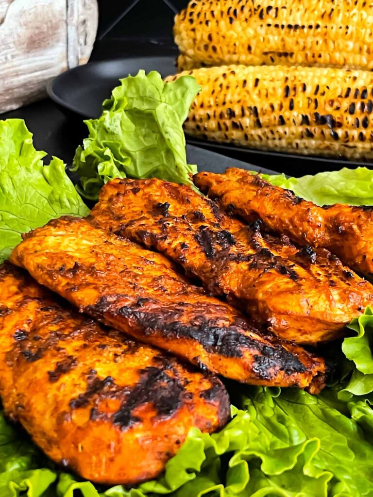 Grilled Southwest chicken with roasted corn in the background.