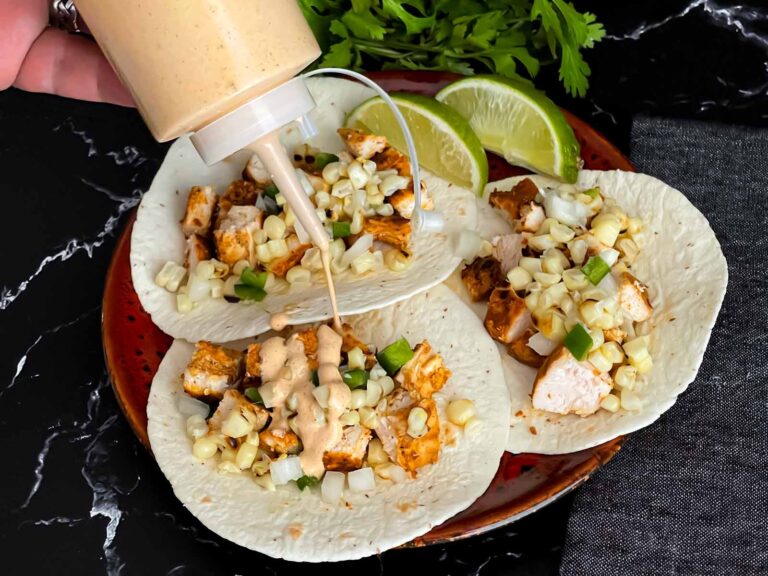 Adding a southwest sauce to grilled chicken tacos.
