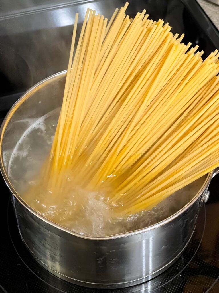 Bucatini just placed in a pot of boiling water.