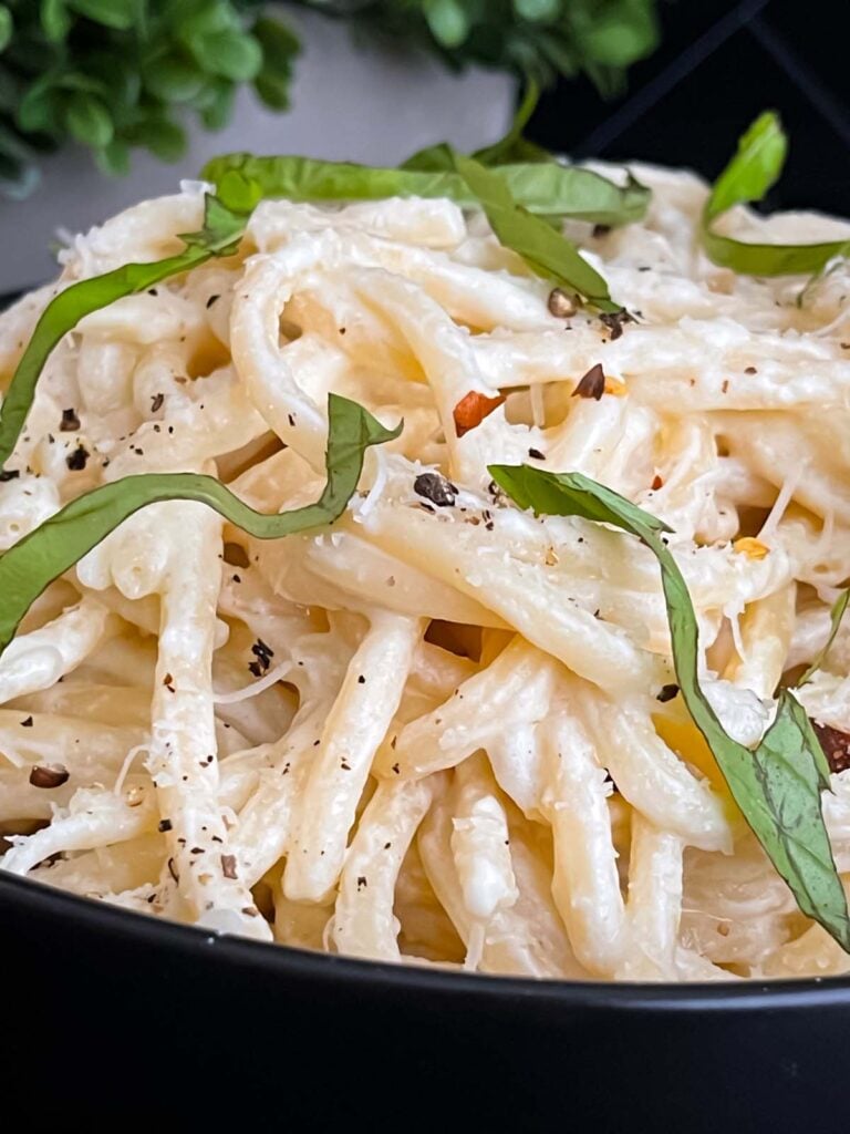 Lemon Ricotta Pasta, topped with black pepper and basil, in a dark bowl.
