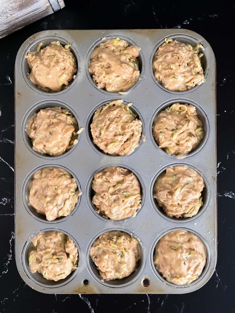 Zucchini muffins, unbaked, in a baking tin.