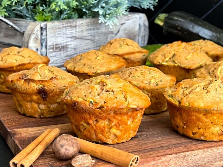 Zucchini muffins on a cutting board with some cinnamon sticks and nutmeg.