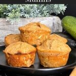 Zucchini muffins on a dark plate with some cinnamon sticks and nutmeg.