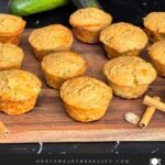 Zucchini muffins on a cutting board with some cinnamon sticks and nutmeg.