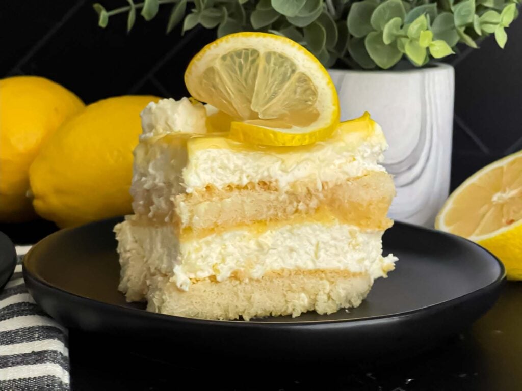 Limoncello tiramisu serving on a dark plate on a dark surface.