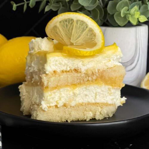Limoncello tiramisu serving on a dark plate on a dark surface.