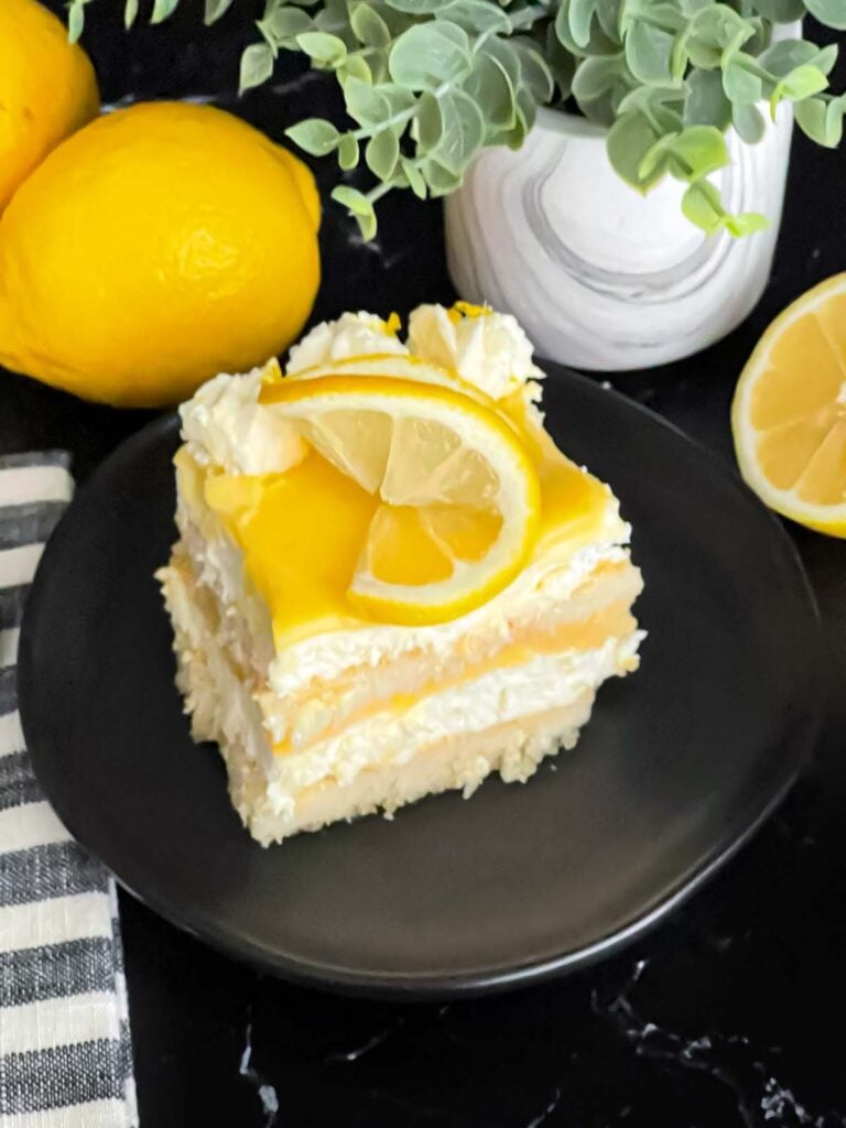Limoncello tiramisu serving on a dark plate on a dark surface.