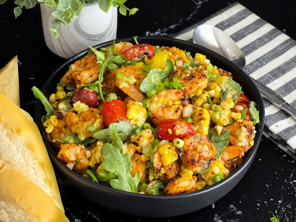 Shrimp and corn salad in a dark bowl.