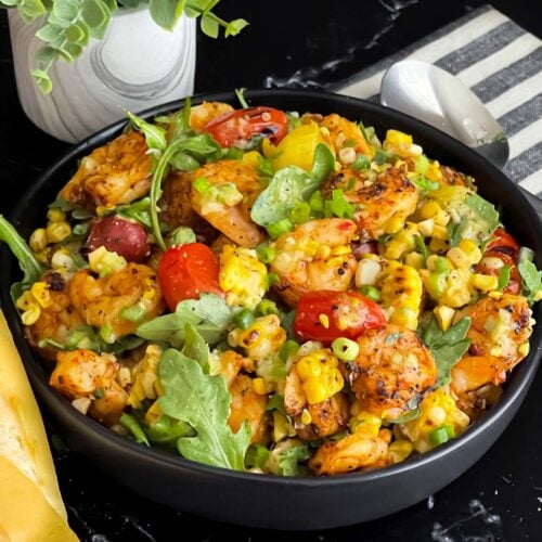 Shrimp and corn salad in a dark bowl.