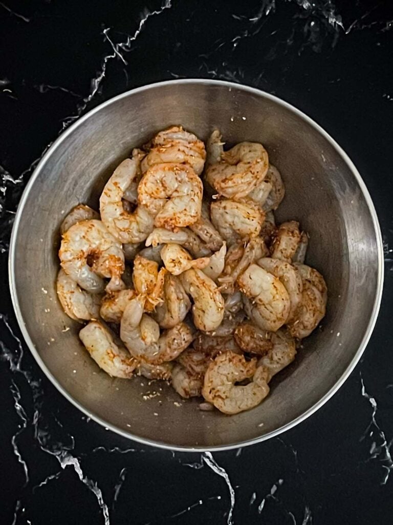 Seasoned raw shrimp in a bowl.