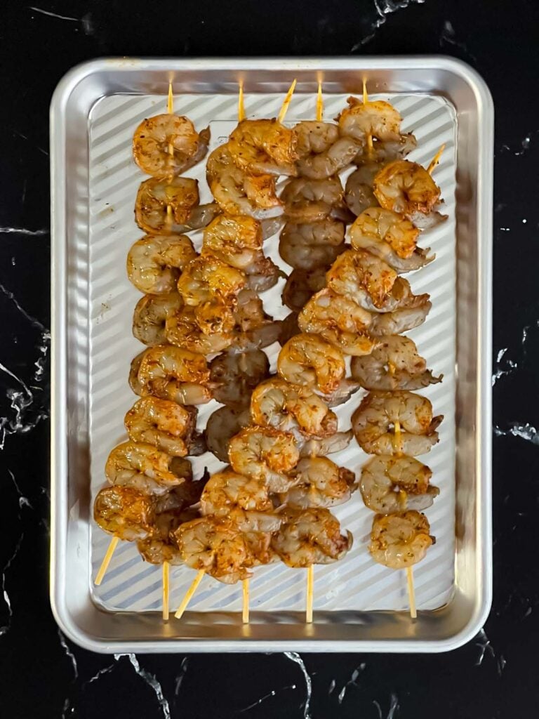 Raw shrimp on wooden skewers.