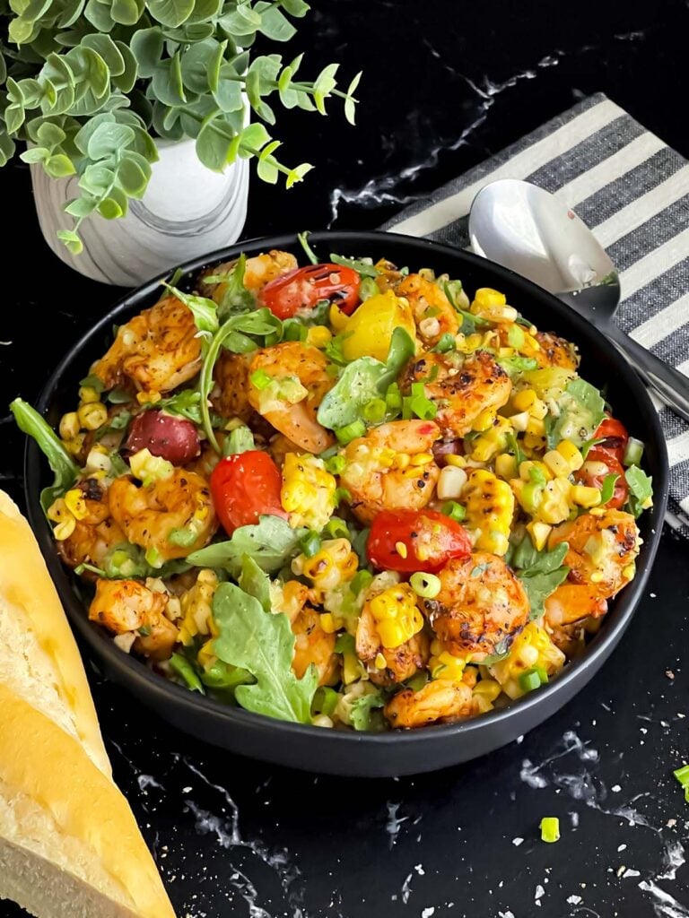 Shrimp and corn salad in a dark bowl.