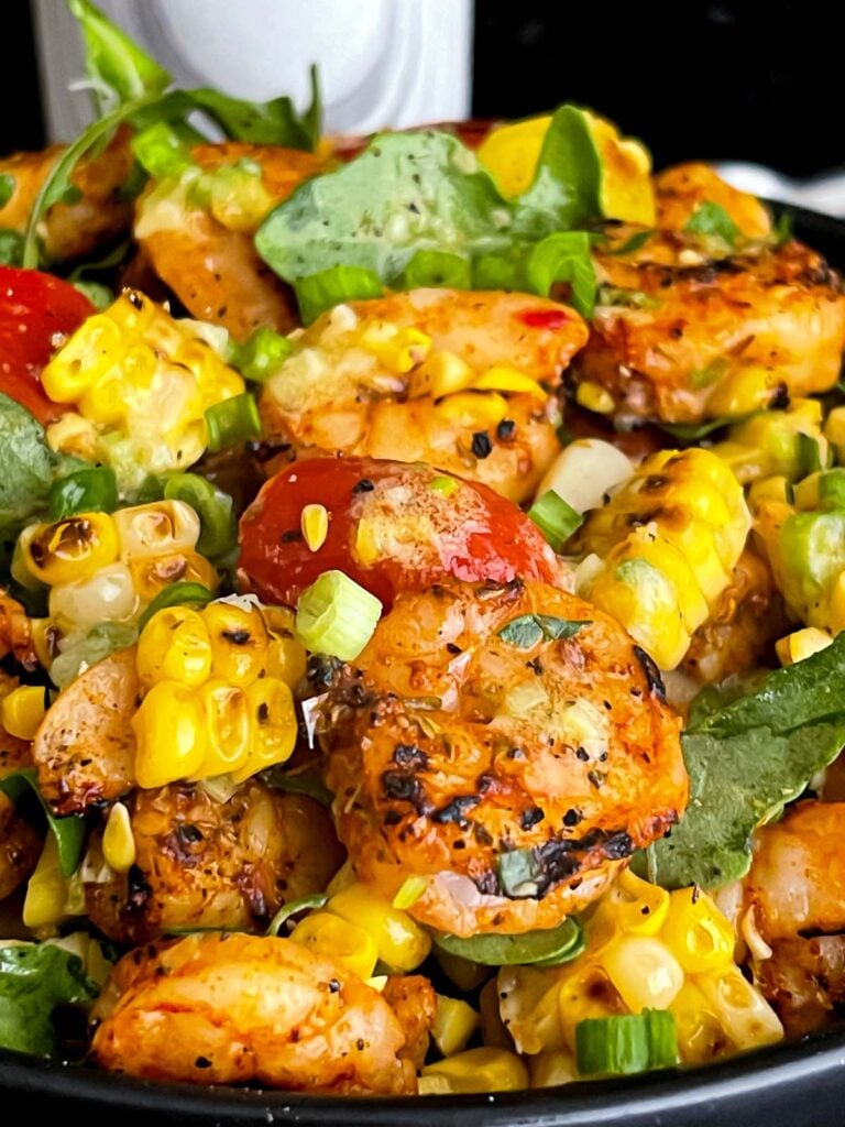 Shrimp and corn salad in a dark bowl.