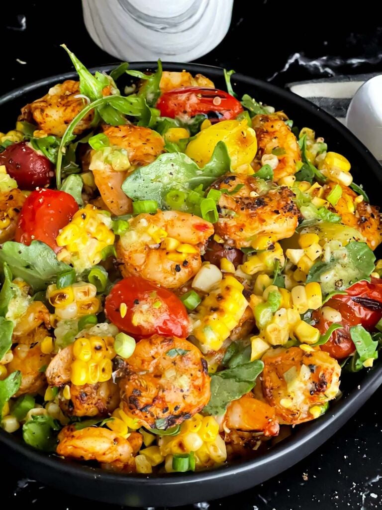 Shrimp and corn salad in a dark bowl.