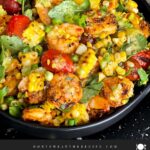 Shrimp and corn salad in a dark bowl.