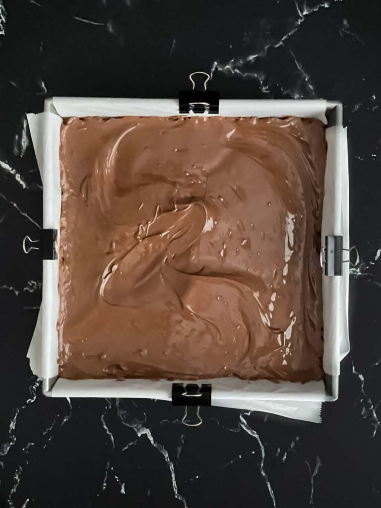 Melted chocolate spread evenly over a graham cracker crust for the s'mores bars.