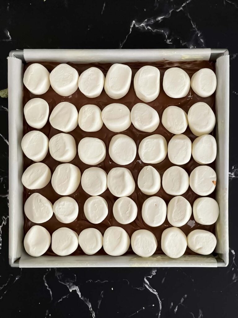 Marshmallows lined over the melted chocolate for s'mores bars.