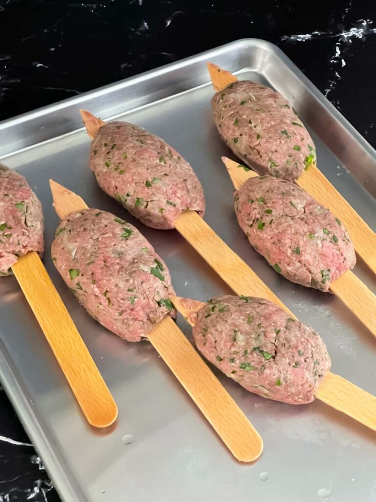 Raw kofte on wooden skewers.