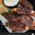 Spiced beef kebabs (kofte) with pita, tzatziki sauce, and a tomato cucumber salad.
