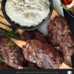 Spiced beef kebabs (kofte) with pita, tzatziki sauce, and a tomato cucumber salad.